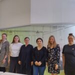 Kuvassa kuusi naista seisoo rivissä ja hymyilee.