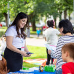 Kuvassa nainen jakaa esitteitä lapsiperheille.