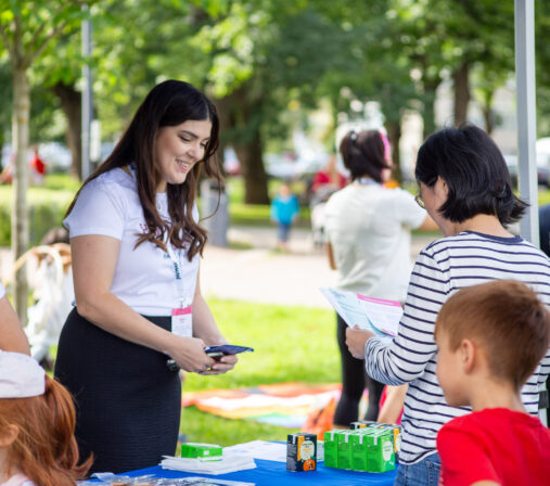 Kuvassa nainen jakaa esitteitä lapsiperheille.