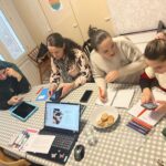 neljä äitiä työskentelee ja juttelee pöydän ääressä