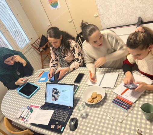 neljä äitiä työskentelee ja juttelee pöydän ääressä