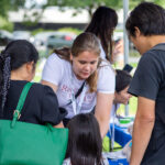 Kotiäitiluotsin työntekijä ottaa ilmoittautumisia vastaan kahdelta osallistujalta