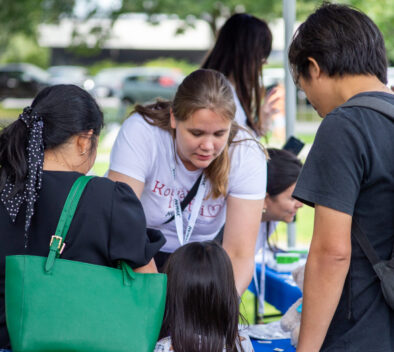 Kotiäitiluotsin työntekijä ottaa ilmoittautumisia vastaan kahdelta osallistujalta