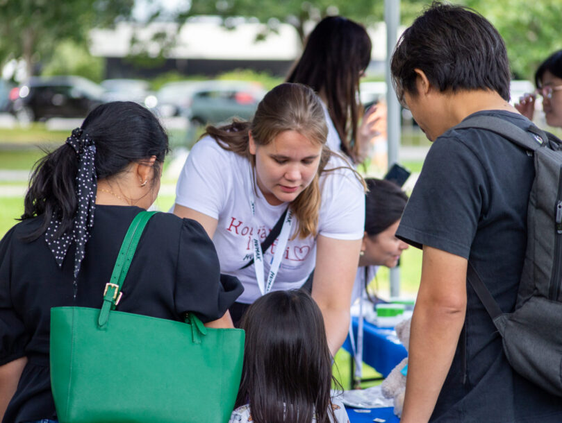 Kotiäitiluotsin työntekijä ottaa ilmoittautumisia vastaan kahdelta osallistujalta