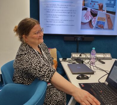 Anette Lindroos ja taustalla ruudulla esitys